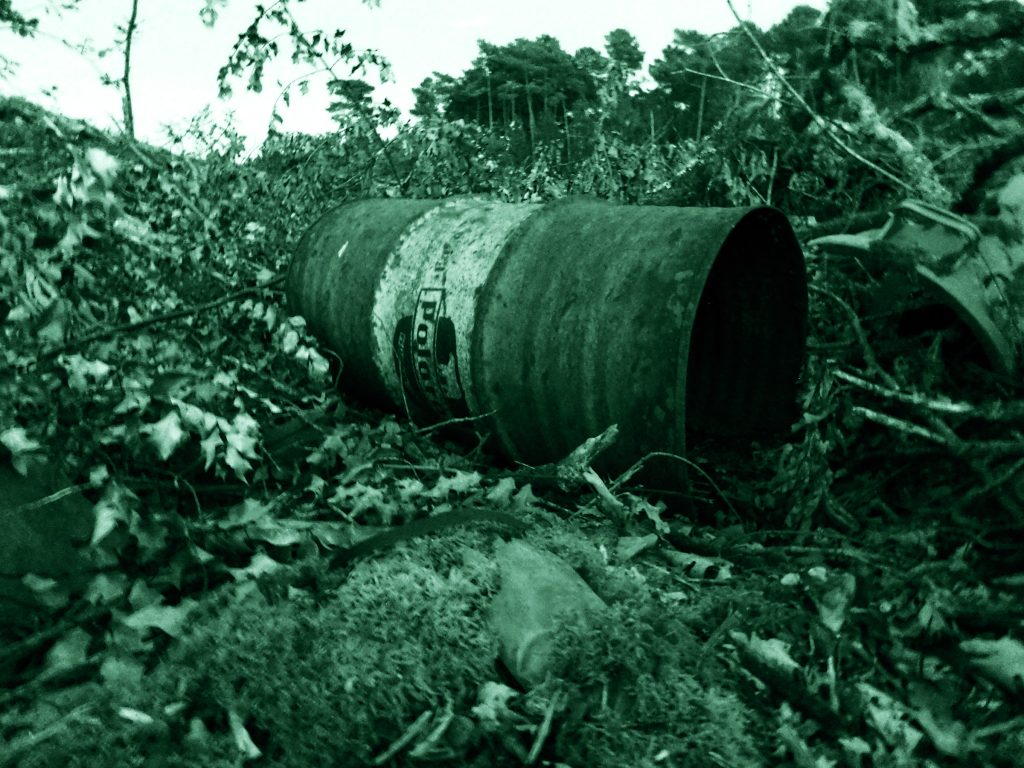 Vecchio barile arrugginito in un bosco, suggestivo di luoghi isolati legati a casi di cronaca nera.