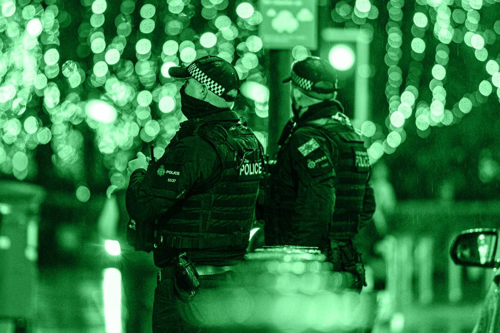 Agenti in tenuta tattica sotto luci notturne, in cerca di un fuggitivo in una strada appartata, simbolo delle cacce all'uomo più grandi della storia.