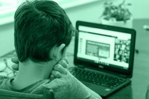 Bambino davanti a un computer, simbolo del fenomeno del cyberbullismo