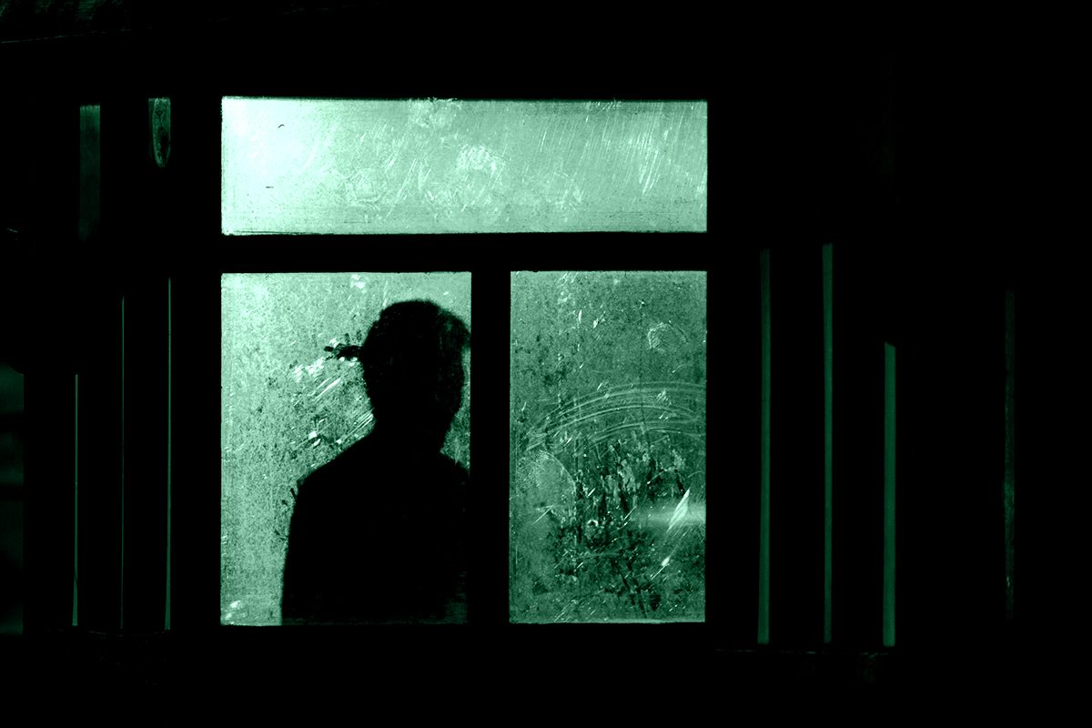 Ombra umana osserva dalla finestra socchiusa: simbolo del voyeurismo come intrusione nell’intimità altrui.